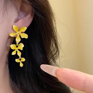 Nahaufnahme gelber Blumen-Ohrhänger mit Emaille-Effekt, getragen an einem Ohr