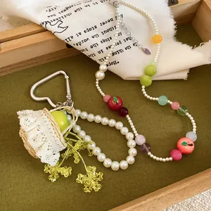 Detailed view of handmade resin apple and pearl beaded necklace with floral keychain set.