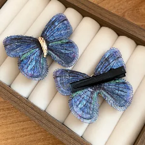 Detail view showing front and back of blue knitted butterfly hair clips in jewelry box