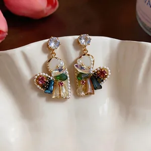 Orecchini a cuore con zirconi colorati e perle su piatto in ceramica decorativo