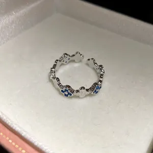 Close-up of elegant silver adjustable ring with inlaid blue zircon flower pattern motifs.