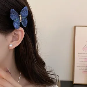 Detailed view of an elegant blue knitted butterfly hair clip worn on woman's side hair.