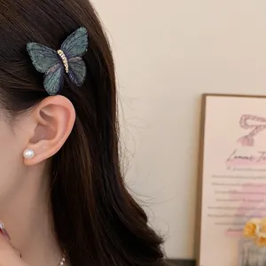 Close-up of an elegant embroidered butterfly hair clip worn on long dark hair.