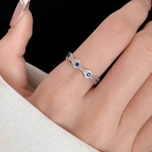 Macro view of a silver textured band ring accented with blue zircon stones on a hand