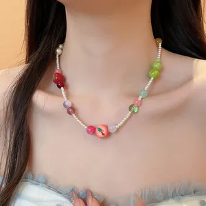 Close-up detail of French resin apple charm and colorful beaded pearl necklace on model