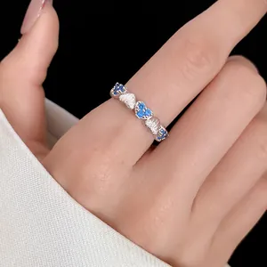 Close-up of a silver heart-shaped ring with sparkling blue zircons on a finger