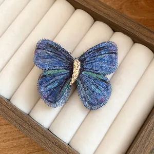 Macro view of blue embroidered butterfly hair clip showing intricate thread texture