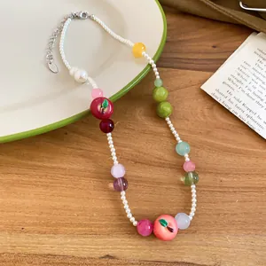 Detailed macro shot of resin fruit beads and pearls on a French style necklace.