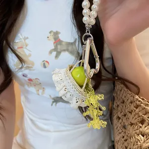 Detail view of a French style resin apple charm featuring pearl beads and a mini lace basket.