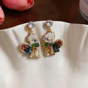 Dettaglio ravvicinato di orecchini a cuore con cristalli colorati e perle eleganti
