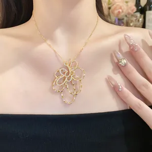 Dettaglio di una collana con pendente a fiore in oro 18k con zirconi indossata da modella