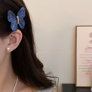 Detailed view of an elegant blue knitted butterfly hair clip worn on a woman's side hair.