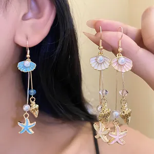 Close-up of beach-style gold seashell and starfish drip oil earrings with pearls.