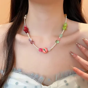 Close-up detail of a French resin fruit and pearl beaded necklace worn by a model.