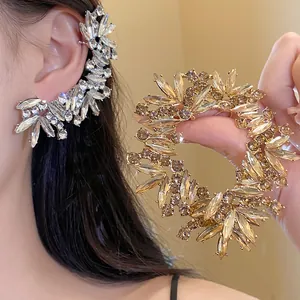 Λεπτομέρεια του πολυτελούς κρυστάλλινου ear cuff και του χρυσού σκουλαρικιού που λάμπει