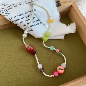 Detailed view of handmade pearl necklace with resin apple and peach charms