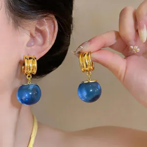 Detailopname van luxe vintage oorbellen met gouden ringen en blauwe harsbollen