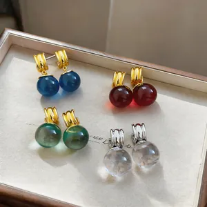 Close-up van kleurrijke harsbal oorbellen in een luxe houten sieradendoosje van kwaliteit.