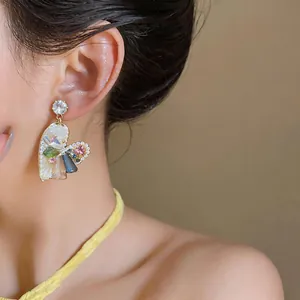 Primo piano dettagliato di un orecchino colorato a forma di cuore con zirconi su modella