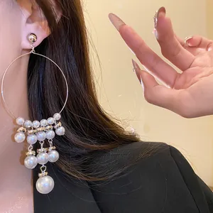 Close-up of elegant silver hoop earrings with multiple pearl tassels on a model's ear.