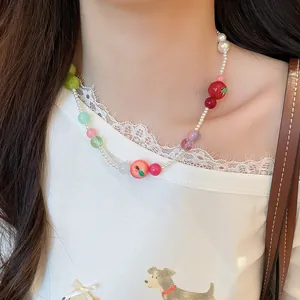 Detailed view of a sweet French resin apple and pearl beaded necklace on a model