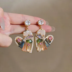 Dettaglio di orecchini a forma di cuore con cristalli colorati e perle eleganti