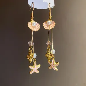 Detailed macro view of gold sea shell starfish earrings with pink enamel and pearls