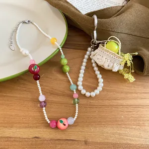 Detail of French resin apple and pearl beaded necklace set on a wooden table.