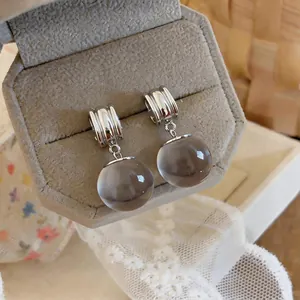 Detail van retro oorbellen met een harsbol-hanger en geribbeld zilveren ontwerp