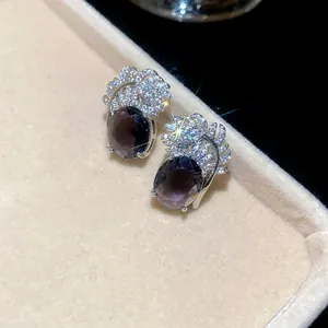 Primo piano di orecchini vintage con piuma di zircone e pietre preziose ovali scure