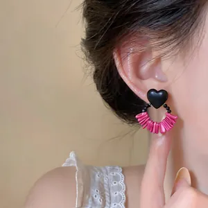 Detailed close-up of vintage heart-shaped earrings with pink beads worn on a model's ear