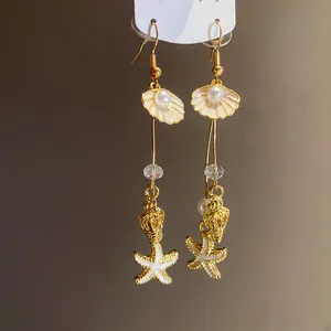 Detailed macro view of elegant starfish and shell pearl dangle earrings for beach vacation.