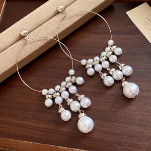 Close-up of elegant pearl tassel earrings with intricate metal beads on a wood tray.