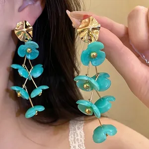 Elegant teal acrylic flower drop earrings with gold accents for a sweet vacation look.