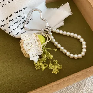 Close-up of a French-style resin apple and pearl beaded keychain with lace straw basket