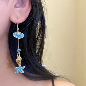 Detail view of beach style blue shell and starfish drop earring with pearl accent