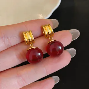 Close-up van vintage gouden oorbellen met grote transparante rode harsbalhangers