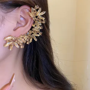 Κοντινό πλάνο πολυτελούς ear cuff με αστραφτερά σαμπανιζέ κρύσταλλα στο αυτί του μοντέλου