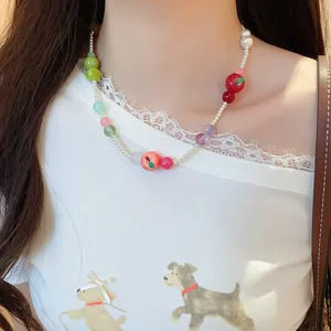Detailed view of a French style resin apple and pearl beaded choker necklace on a model.