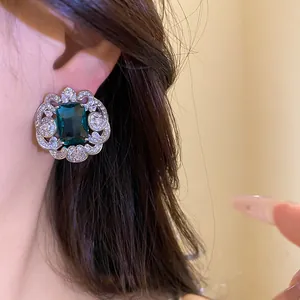 Gros plan d'une élégante boucle d'oreille en zircon vert émeraude bordée d'argent
