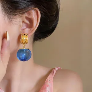 Detailopname van retro gouden oorringen met een doorschijnende blauwe hanger