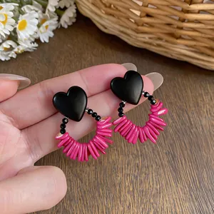 Close-up detail of retro ethnic heart earrings crafted with black wood and pink beads