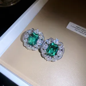 Gros plan d'élégantes boucles d'oreilles émeraude avec un halo de zircons brillants