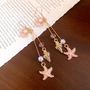 Detailed view of pink shell and starfish dangle earrings with pearls.