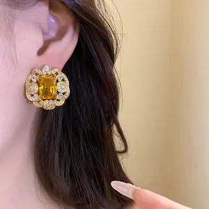 Vue détaillée d'une boucle d'oreille en or avec un grand zircon jaune sur le modèle