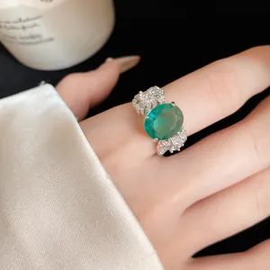 Vista dettagliata di un anello vintage con zircone verde ovale e piume su un dito