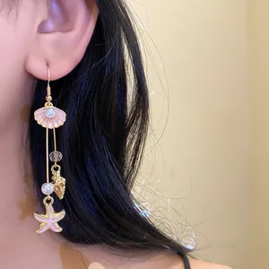 Detailed view of beach-style dangling earrings with pink shell, starfish, and pearls