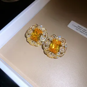 Gros plan de boucles d'oreilles dorées avec zircon jaune et détails en filigrane