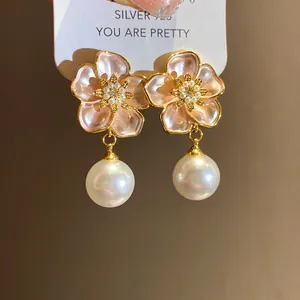 Macro detail of elegant pink enamel flower earrings with white pearls and zirconia accents