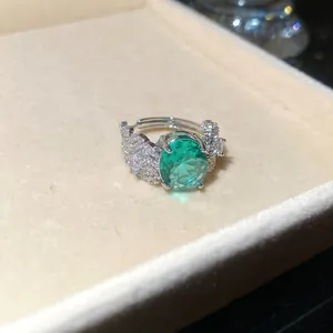 Dettaglio macro di un anello in stile palazzo con zircone verde ovale e piume.